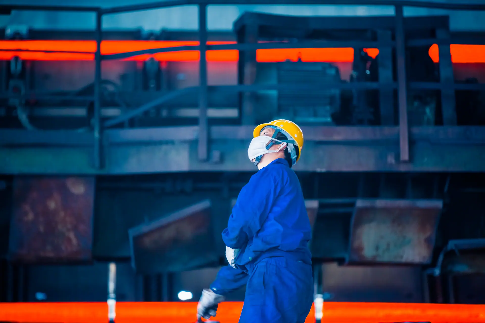 Site industriel en lumière chaude, un opérateur devant une ligne de production
